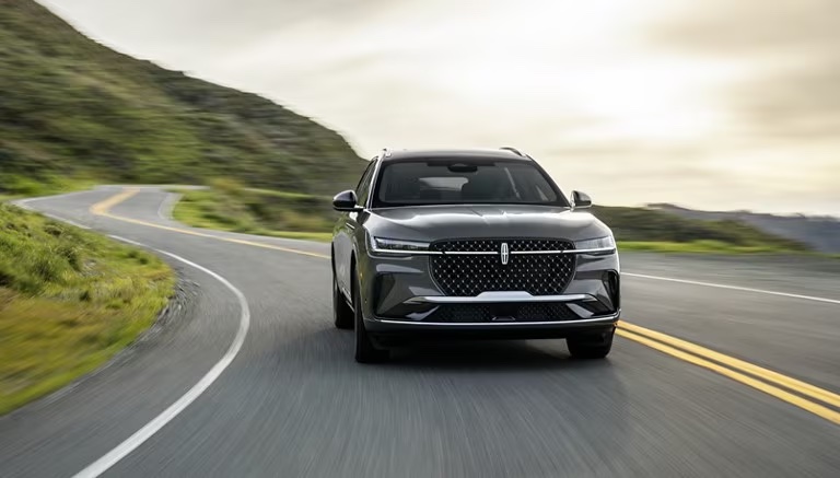 SUV driving on a road with a hill in the background