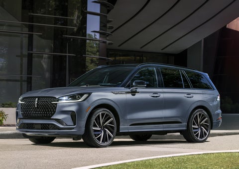 A gray 2025 Lincoln Aviator® SUV is parked outside a modern building showcasing the driver’s side of the vehicle. | Beach Lincoln in Myrtle Beach SC