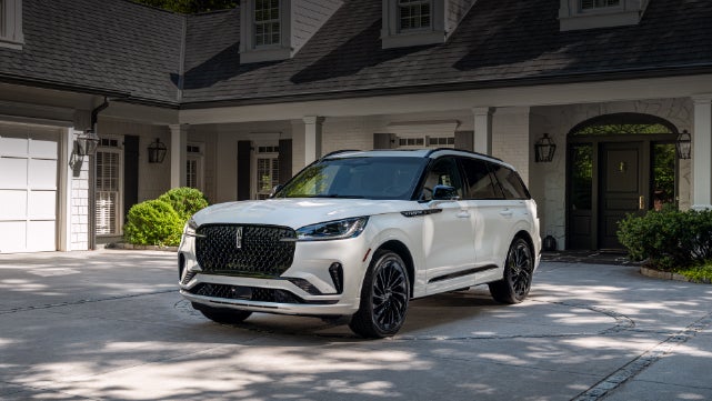 A white 2026 Lincoln Aviator® SUV is parked in the driveway of a luxury home. | Beach Lincoln in Myrtle Beach SC
