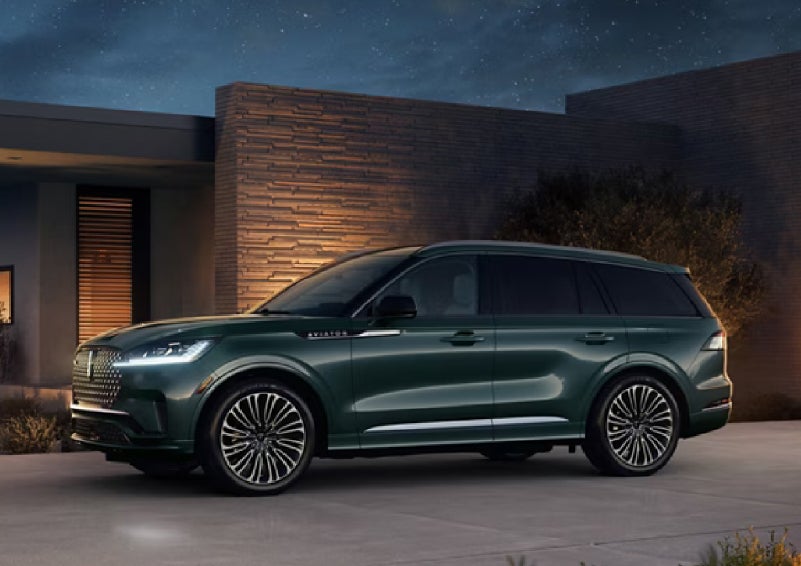 A green 2027 Lincoln Aviator® SUV is parked outside a contemporary home. | Beach Lincoln in Myrtle Beach SC