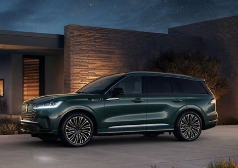 A green 2027 Lincoln Aviator® SUV is parked outside a contemporary home. | Beach Lincoln in Myrtle Beach SC