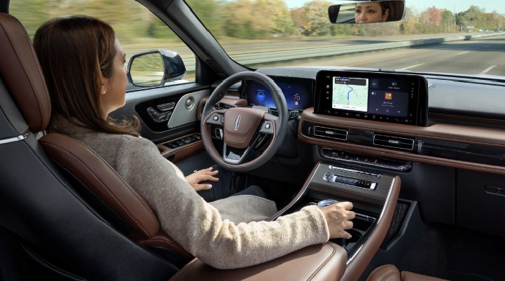 A 2027 Lincoln Aviator® SUV is being driven hands-free on a highway lined with trees. | Beach Lincoln in Myrtle Beach SC