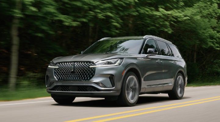A 2027 Lincoln Aviator® SUV is being driven down a road lined with trees. | Beach Lincoln in Myrtle Beach SC
