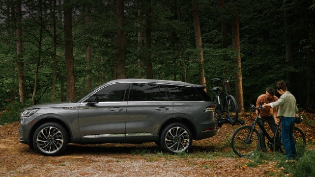 A father and son load e-bikes on a bike rack attached to a 2027 Lincoln Aviator® SUV. | Beach Lincoln in Myrtle Beach SC