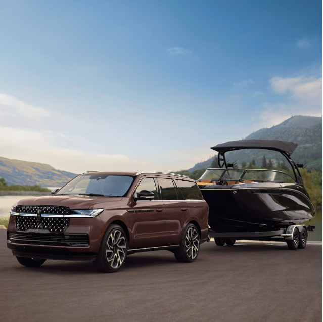 A luxury brown SUV is parked on a paved road