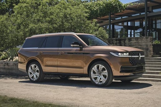 White SUV parked on a city street in front of a building 